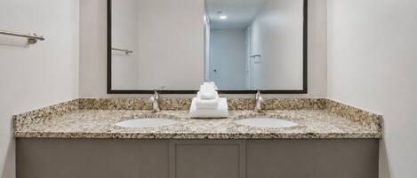 A bathroom with a double sink vanity, a large mirror, and overhead lighting.