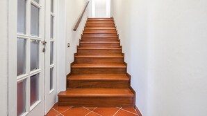 A wooden staircase with white walls and a tiled floor leading to a door with frosted glass panels. - Cozy home in Fucecchio with WiFi (Fucecchio)