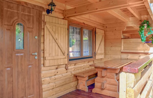 A wooden cabin interior with a door, a window with shutters, a bench, and a small table. - 2 bedroom nice home in Sianozety (Sianozety)