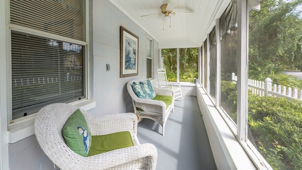 A covered porch with wicker chairs and a ceiling fan. - Historic Tremain  Cottages (Mount Dora)