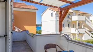 A balcony with a view of the sea, a wicker chair, and a table with a blue tablecloth. - 1 bedroom beautiful apartment in Barbat na Rabu (Barbat na Rabu)