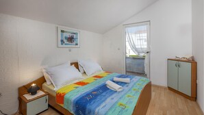 A bedroom with a bed, a nightstand, a wardrobe, a painting on the wall, and a balcony with a view. - 1 bedroom beautiful apartment in Barbat na Rabu (Barbat na Rabu)