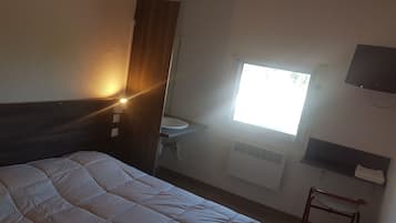 Una habitación de hotel con cama, ventana, lavamanos y televisión.