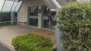 A hotel entrance with a ramp leading up to the door, a bench outside, and a sign indicating it is an eco-friendly hotel.