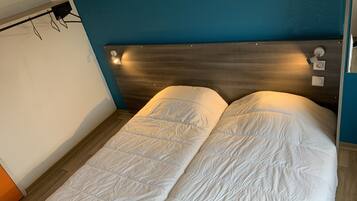Uma cama de casal com cabeceira de madeira e duas luminárias de cabeceira.