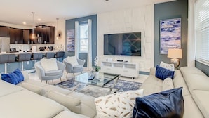 A modern living room with a sofa, armchairs, a coffee table, and a TV. - Imperial Retreat: Games,Pool,Theatre + Free Night (Champions Gate)