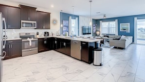 A modern kitchen with dark cabinetry, stainless steel appliances, and a central island. - Imperial Retreat: Games,Pool,Theatre + Free Night (Champions Gate)