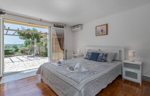 A bedroom with a large bed, two bedside tables, a window with a view, and an air conditioning unit. - Beach front apartment in Crikvenica with WiFi (Crikvenica)