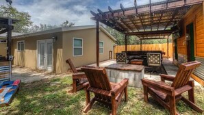 Eine Terrasse mit Holzstühlen, einer Feuerstelle und einer Pergola.