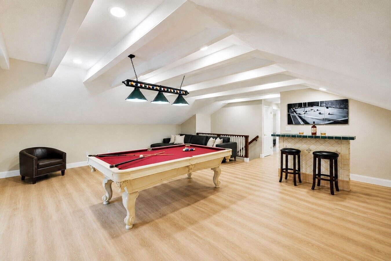 Une table de billard dans une pièce dotée d’un plafond haut et d’un plancher en bois.