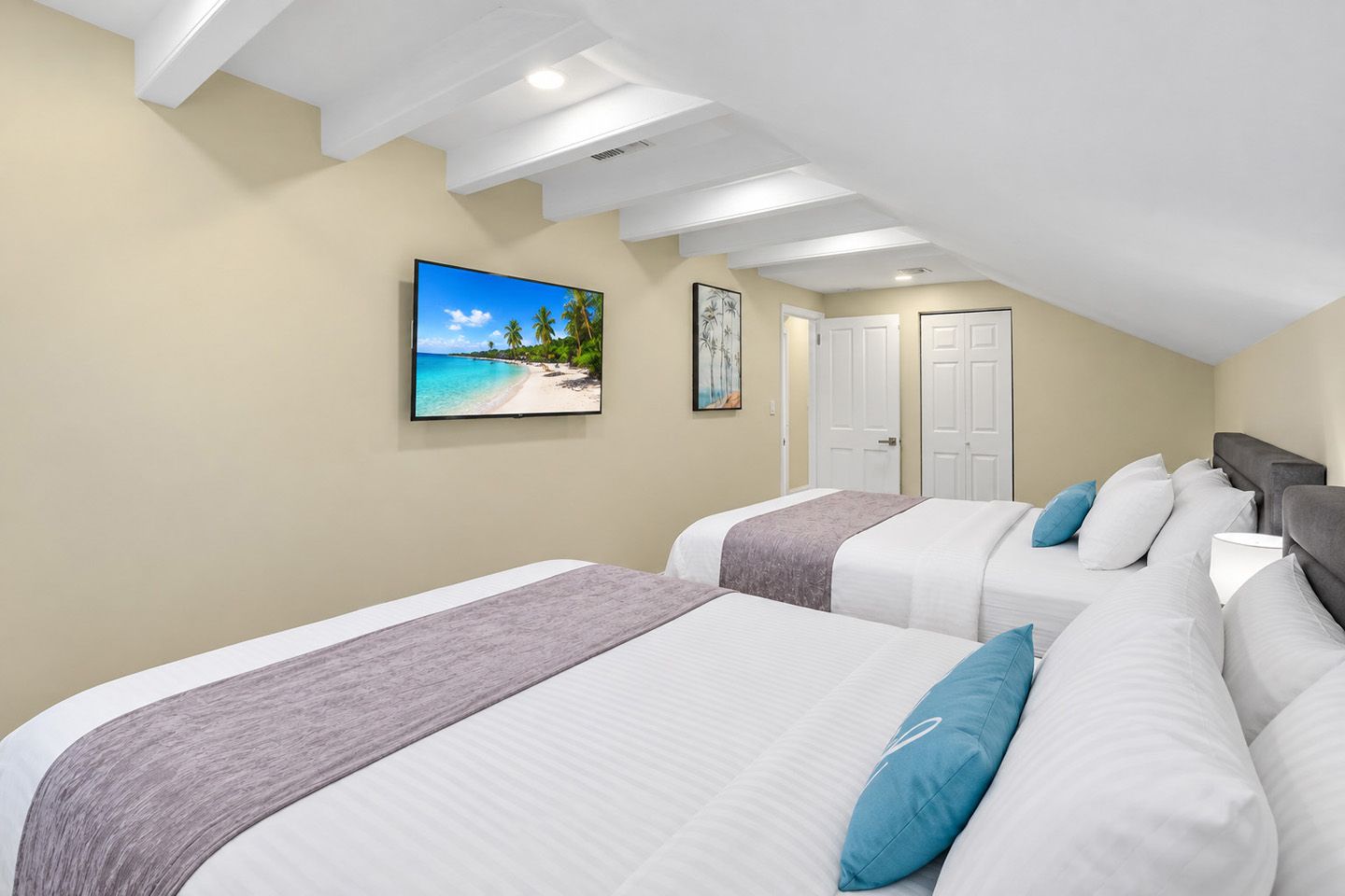 A hotel room with two beds, a large window with a beach view, and a ceiling with recessed lighting.