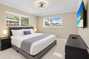 Una habitación de hotel con cama, mesitas de noche, escritorio y televisor.
