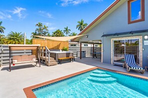Un espace aménagé au bord de la piscine, comprenant un jacuzzi, des chaises longues et un coin salon abrité.