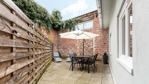 A patio with a brick wall, wooden fence, and a table with chairs. - Le Moja Tourcoing (Tourcoing)