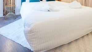 A modern bedroom with a large bed, a wooden accent wall, and a hanging light fixture. - Le Moja Tourcoing (Tourcoing)