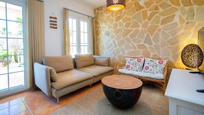 A living room with a stone wall, a sofa, a coffee table, and a hanging light fixture. - Nice apartment in villa for 4 people with A/C, WIFI, pool, TV and terrace (Calpe)