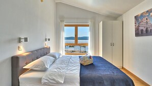 A bedroom with a bed, a view of the sea, a window, and a painting on the wall. - Beautiful home in Turanj (Turanj)