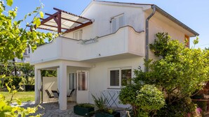 A two-story house with a covered patio, outdoor seating, and a garden area.