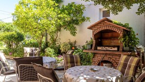 An outdoor patio with a brick oven, round table, and chairs.