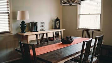 Un coin repas comprenant une table en bois, des chaises, un banc, une lampe et un luminaire suspendu.