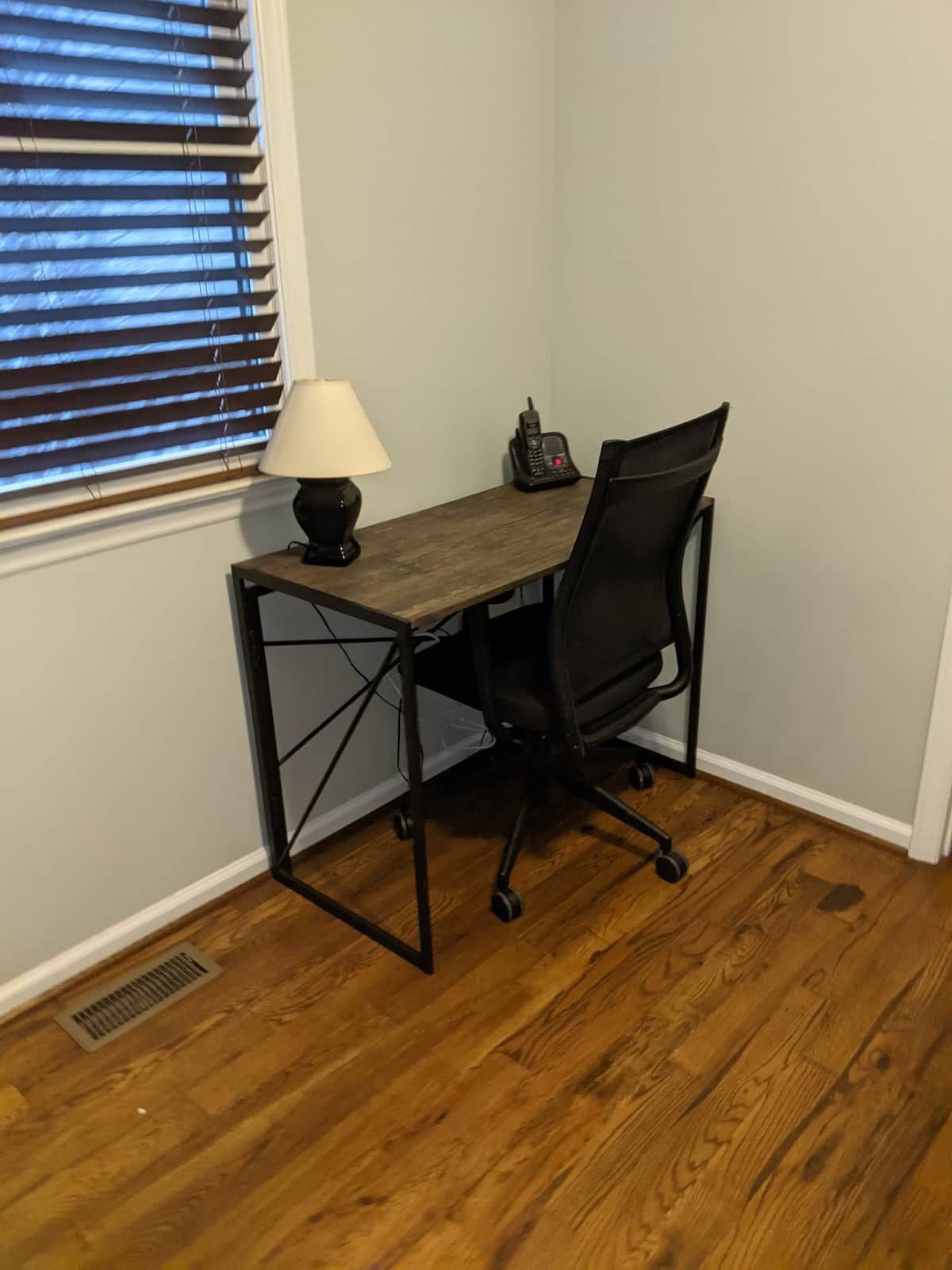 Ein Eckbüro mit Schreibtisch, Stuhl, Lampe und Telefon.