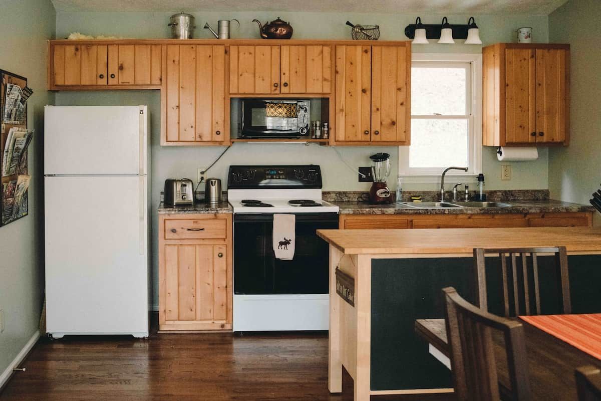 A kitchen with wooden cabinets, a refrigerator, a stove, a microwave, and a sink.