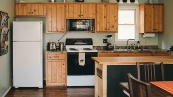 A kitchen with wooden cabinets, a refrigerator, a stove, a microwave, and a sink.