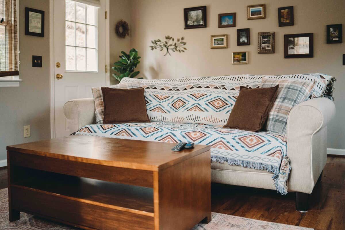 Una sala de estar con un sofá, una mesa de centro de madera y una pared decorada con marcos de fotos.