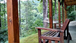 A wooden bench in a forested area with a hammock and wooden beams.