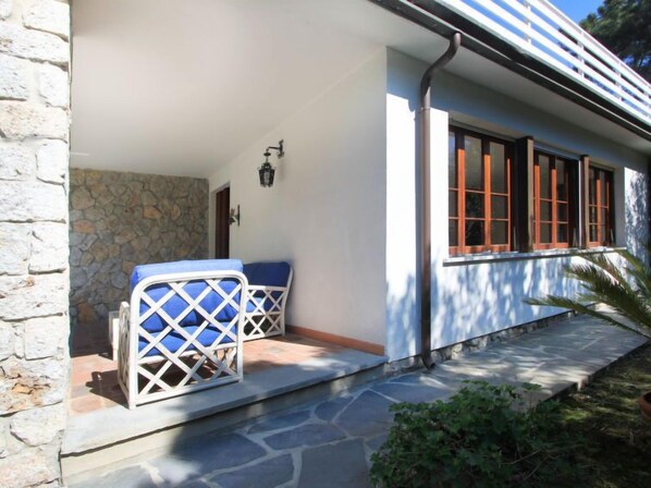 A stone house with a covered porch, a stone wall, and a window with wooden shutters. - Vacation home Silvia by Interhome (Forte dei Marmi)