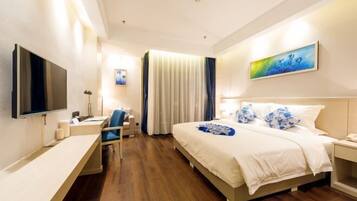 A modern hotel room with a large bed, a desk, a flat-screen TV, and a painting on the wall.