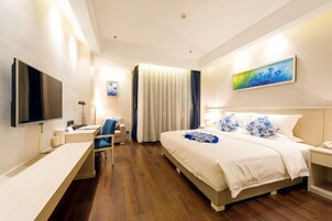 A modern hotel room with a large bed, a desk, a flat-screen TV, and a painting on the wall.