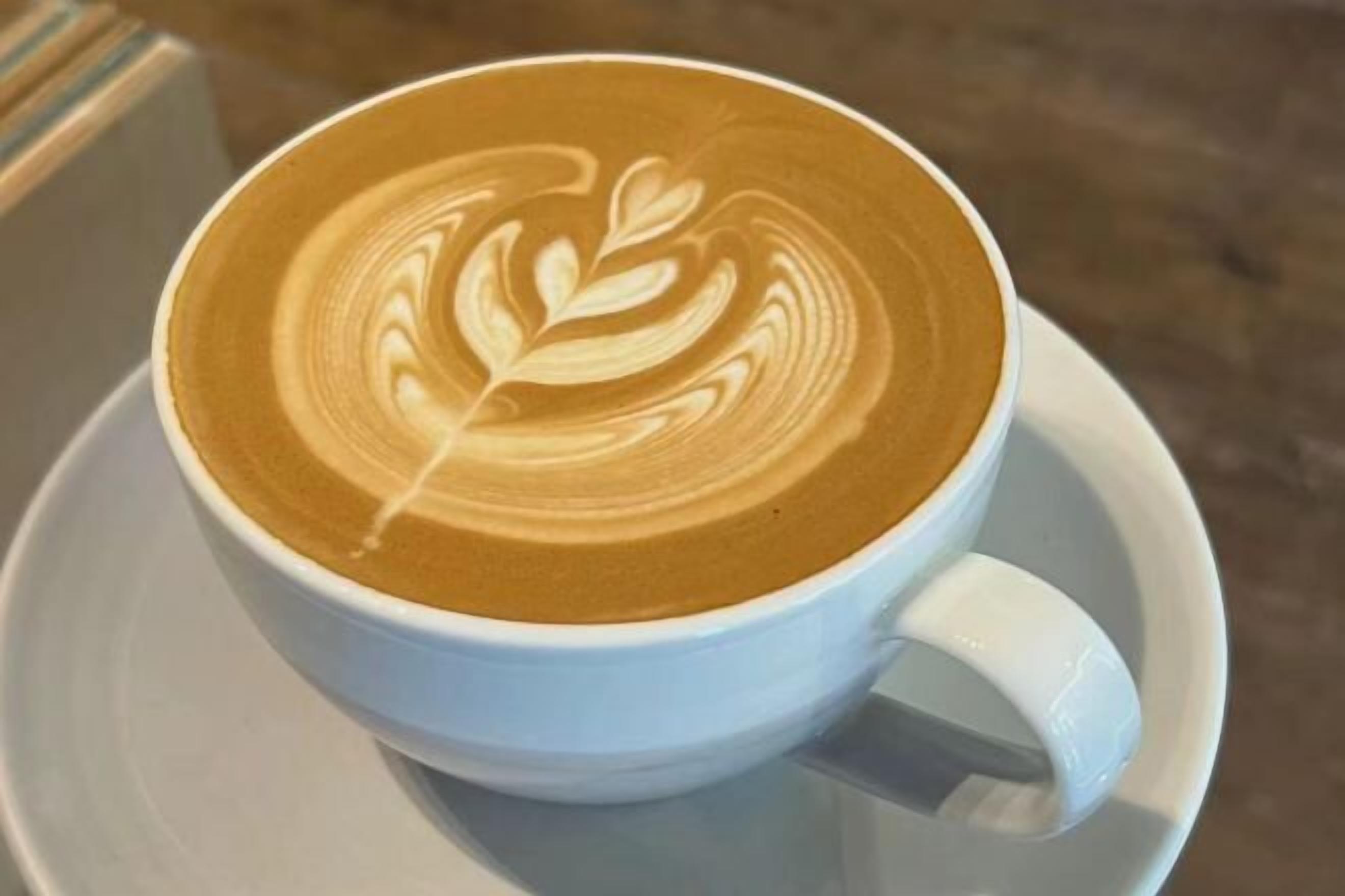 Une tasse de café avec un motif en latte servi sur une soucoupe.