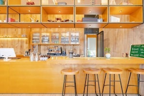 A wooden interior with a bar area, stools, and a green menu board.