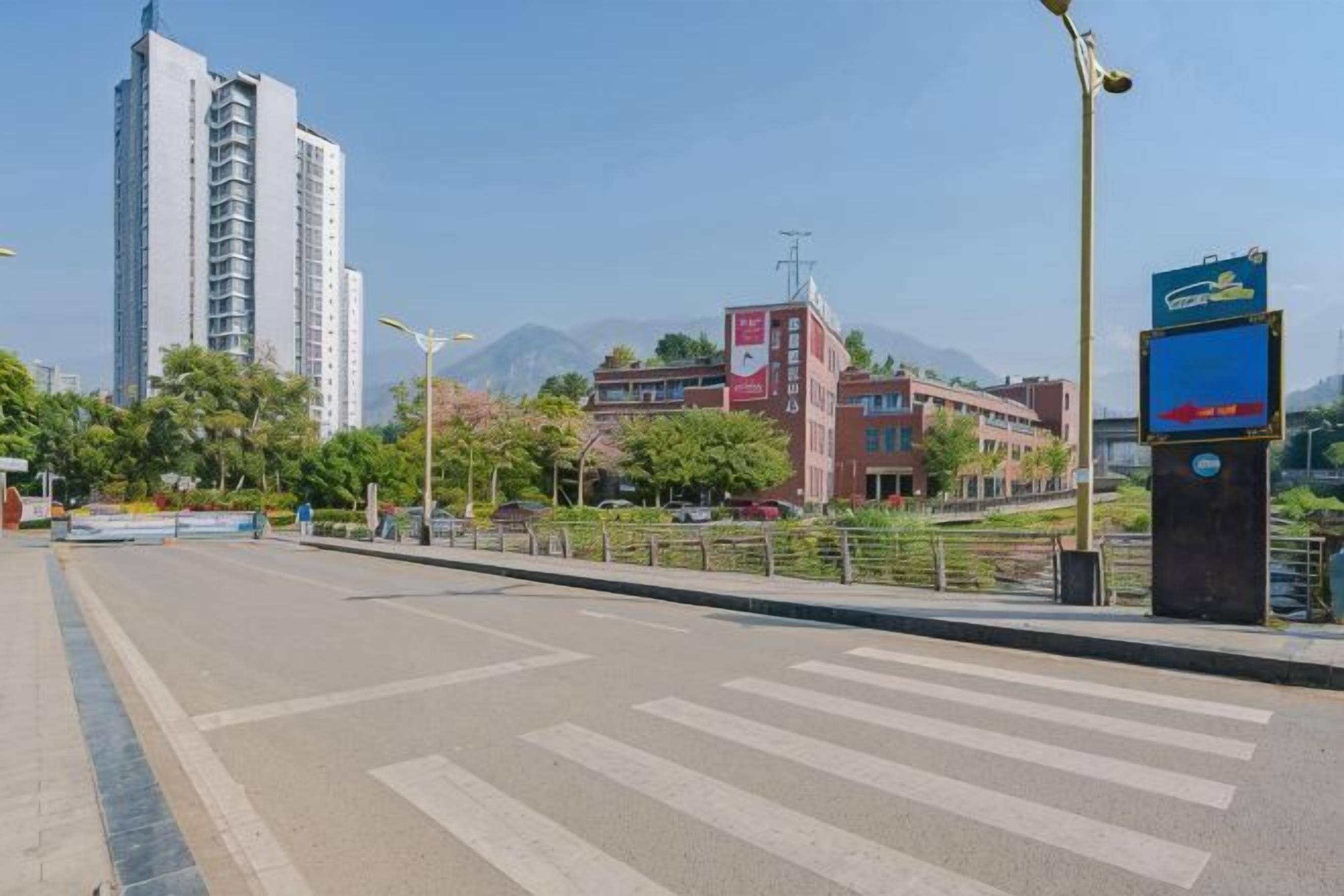 A wide street with a pedestrian crossing, a tall building, and a signboard.