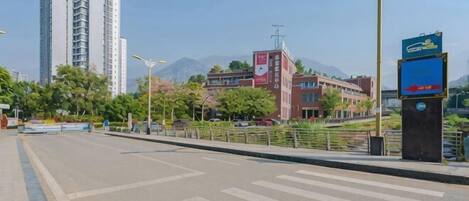 A wide street with a pedestrian crossing, a tall building, and a signboard.