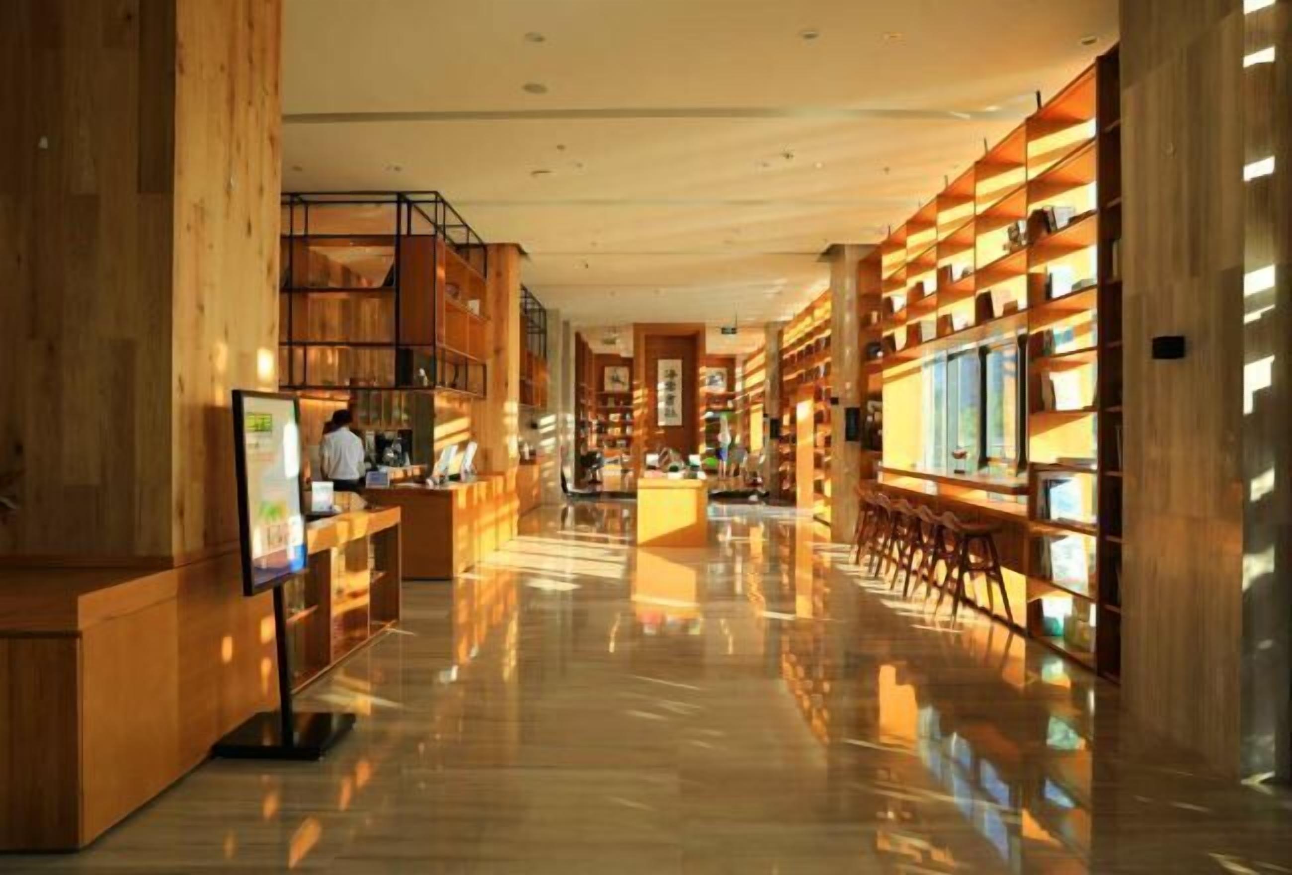 A spacious library with wooden bookshelves and a polished floor.