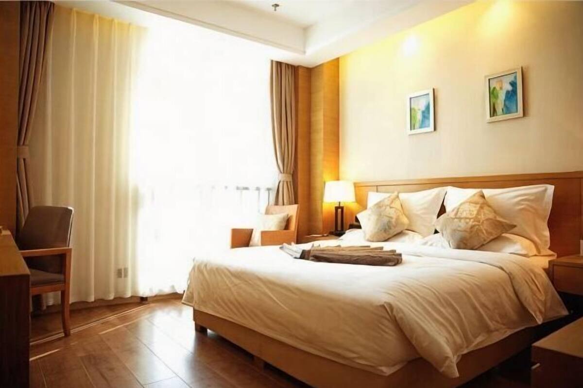 A hotel room with a large bed, a chair, a nightstand, and a lamp.