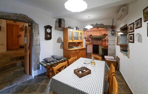 A cozy dining area with a checkered tablecloth, wooden chairs, and a small side table with candles.
