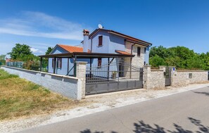 Une maison à deux étages avec un mur en pierre et un portail en métal.