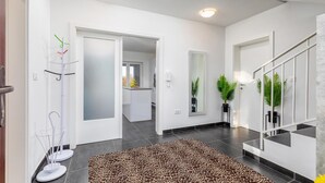 A modern interior with a staircase, a hallway leading to a kitchen, and a living area with a giraffe-patterned rug. - Luxurious home in Sosici (Sosici)