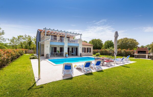 Une maison à deux étages dotée d’une piscine, d’un espace extérieur aménagé et d’un coin barbecue.