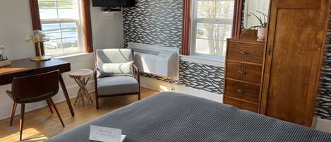Ein Hotelzimmer mit Bett, Schreibtisch, Stuhl, Kleiderschrank und Fernseher.