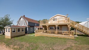 Una casa de dos pisos con una terraza de madera y una escalera que lleva a un balcón.