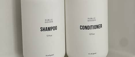 Dos botellas blancas de champú y acondicionador de Public Goods, cada una con un volumen de 355 ml y la frase 'it's all good'.