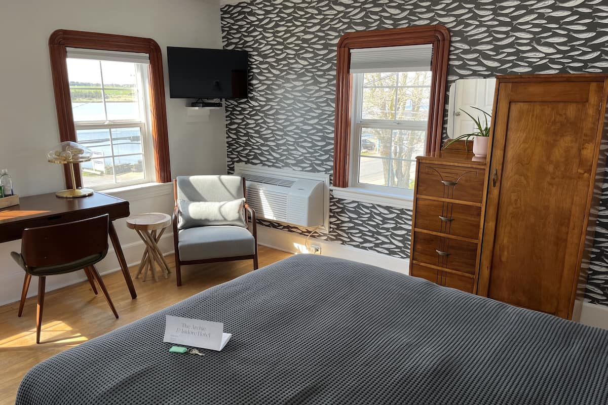 Ein Hotelzimmer mit Bett, Schreibtisch, Stuhl, Fernseher und Kleiderschrank.