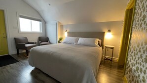 Un dormitorio con una cama grande, dos sillas, una mesita y una ventana.