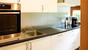 Una cocina moderna con electrodomésticos de acero inoxidable, armarios blancos y una encimera de granito negro.