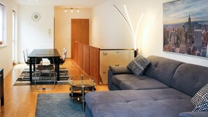 Una sala de estar moderna con un sofá gris, una mesa de centro de vidrio y un comedor con una mesa y sillas negras.