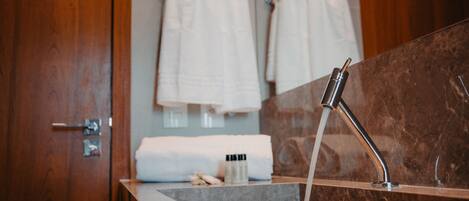 A bathroom with a marble sink, a modern faucet, and a wooden door.
